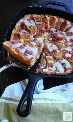 a pizza in a cast iron skillet with one slice cut out and ready to be eaten