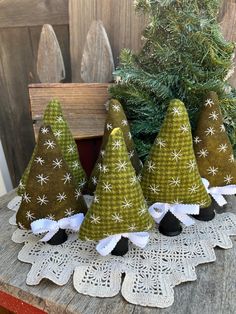 three green christmas trees sitting on top of a wooden table