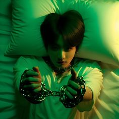 a person laying in bed with chains around their neck and hands on the pillow,