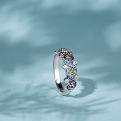 a white gold ring with blue and yellow diamonds