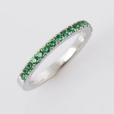 a white gold ring with green stones