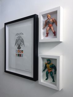 two framed action figures on the wall next to each other in black and white frames