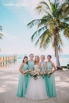 the bride and her bridesmaids pose for a photo on the beach in front of palm trees