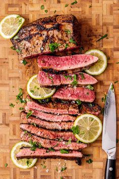 steak with lemon wedges and parsley on a cutting board next to a knife