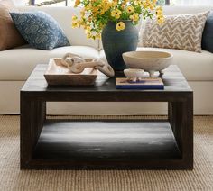 a living room filled with furniture and flowers on top of a coffee table in front of a white couch