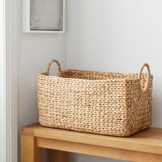 a wicker basket sitting on top of a wooden table next to a white wall