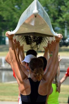 a group of people standing around each other holding something on their head in the air