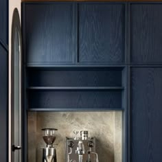 a kitchen with blue cabinets and stainless steel coffee maker on the counter top, in front of an open door