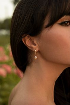 The dainty and romantic Avril pearl earrings are perfect for everyday wear, but can also be dressed up for a night out. Peach-tinted freshwater pearls add a touch of charm and delicacy while 14k gold-filled hoops a sense of luxury.   -13mm 14k gold-filled huggie hoops -Peach-tinted freshwater pearls  -Hypoallergenic, suitable for even the most sensitive skin -Delivered in a limited edition hand-embroidered bag with a pink jewelry pochette and card inside -Sustainable packaging   Please note, as Everyday Teardrop Pearl Pendant Earrings, Feminine Pearl Drop Jewelry, Minimalist Pearl Earrings For Everyday Elegance, Minimalist Single Pearl Earring For Everyday Elegance, Elegant Everyday Pearl Earrings With Charm, Elegant Everyday Pearl Pendant Earrings, Elegant Rose Gold Earrings For Everyday Elegance, Everyday 14k Gold Filled Pearl Pendant Earrings, Elegant Earrings With Pearl Charm For Everyday