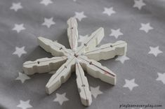 a snowflake made out of white wooden sticks on a gray and white blanket