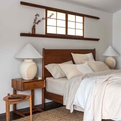 a bed with white sheets and pillows in a bedroom next to two lamps on either side of the bed