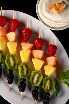 fruit skewers are arranged on a white plate