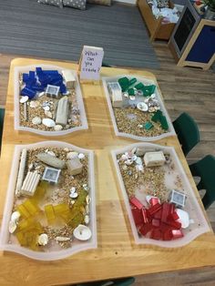 three plastic trays filled with sand and sea glass on top of a wooden table