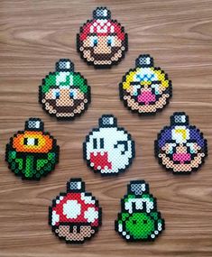 six pixelated video game character magnets on a wooden surface, each with different colors and sizes