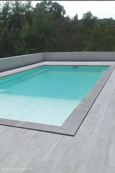 an empty swimming pool in the middle of a patio with wooden flooring and walls