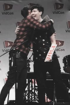 two young men hugging each other on stage