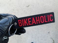 a close up of a person wearing gloves and holding onto a sign that says bikeaholic