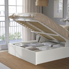 a white bed with an open storage compartment in the middle and pillows on it's sides