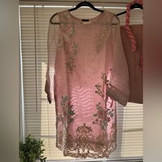 a pink dress hanging on a rack in front of a window