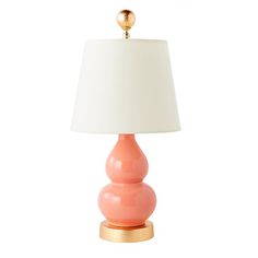 an orange lamp with a white shade on the base and a gold ball at the top