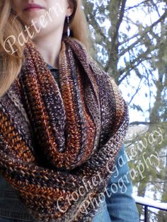 a woman wearing a brown and black knitted cowl in front of some trees