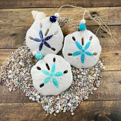 three sand dollar ornaments with sea shells and starfishs on top of the sand