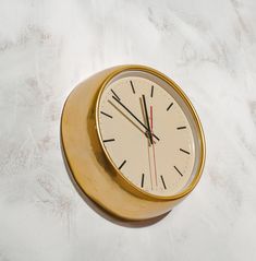 a gold clock with black hands on a white surface