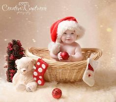 a baby sitting in a basket next to two teddy bears wearing santa hats and holding an apple