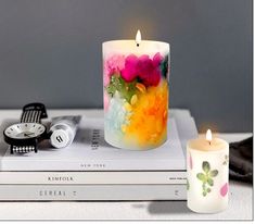 two candles sitting on top of books next to each other