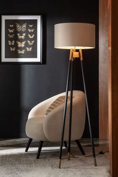 a lamp sitting on top of a wooden floor next to a chair and framed pictures