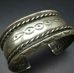 "VINTAGE NAVAJO BRACELET DESCRIPTION: This old hand wrought Navajo cuff bracelet features intricate designs. The hand-stamped edges are carinated, and thick twisted silver wire serves as an additional border. From the Frank Kinsel collection, this collectible bracelet will be a cherished addition to your collection of the very finest vintage Native American jewelry. MEASUREMENTS: Interior of the cuff measures 5 1/2\" with an additional 1 1/8\" slightly adjustable gap. Total circumference: 6 5/8\ Classic Adjustable Cuff Bracelet With Intricate Design, Traditional Stamped Cuff Bangle, Antique Etched Adjustable Cuff Bracelet, Traditional Etched Cuff Bracelet, Traditional Etched Cuff Jewelry, Antique Silver Stamped Bangle Bracelet, Vintage Antique Silver Stamped Bracelets, Vintage Oxidized Bangle Cuff Bracelet, Classic Stamped Cuff Bracelets