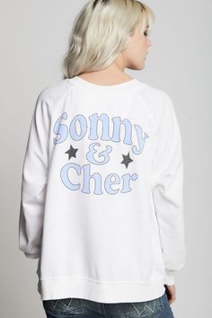 This sweatshirt is an absolute must have for any Sonny & Cher fan. The front features the duo's names and a photo graphic of the icons with their song "Bring It On Home To Me" below. "Sonny & Cher" is also featured on the back with stars. Made with vintage washed fabric, ribbed hems, a relaxed crew neckline, and an oversized fit. The design of this style is oversized. For a more standard fit, choose a size down. Details Style #302270 Color: White Sonny & Cher Bring It On Home To Me Oversized Swe White French Terry Top With Graphic Print, Graphic Print French Terry Crew Top, French Terry Crew Top With Graphic Print, Graphic Print Crew Top In French Terry, Graphic Print Crew Neck Top In French Terry, White Oversized Band Merch Sweatshirt, White Screen Print Band Merch Sweatshirt, White Letter Print Sweatshirt For Concert, Relaxed Fit Sweatshirt With Screen Print For Concert