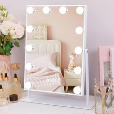 a white vanity mirror sitting on top of a table next to a vase with flowers