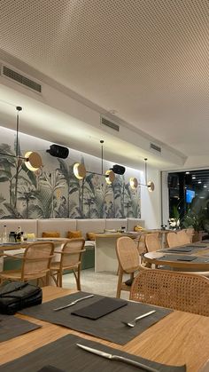 an empty restaurant with wooden tables and wicker chairs in front of a wall mural