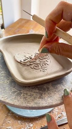 a woman is painting a ceramic dish with paintbrushes