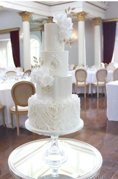 a white wedding cake sitting on top of a glass plate in front of a table