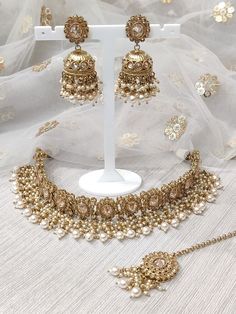 the necklace and earrings are on display in front of a white background with gold flowers