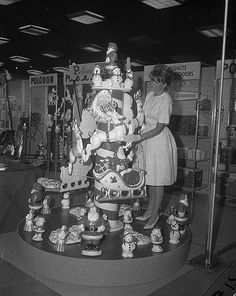 an old black and white photo of a woman standing next to a christmas tree