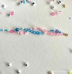 beads and charms are scattered around the word hello written on a sheet of white paper