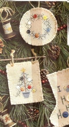 two christmas ornaments hanging from a tree with pine cones and other decorations on it's sides