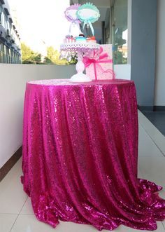 a table with a pink sequin covered cake on it's centerpiece and an umbrella in the background