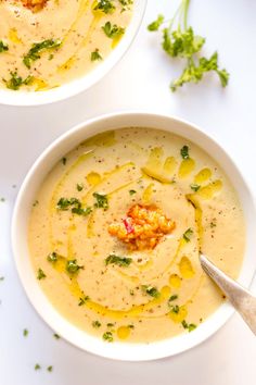 two white bowls filled with soup and garnished with parsley on the side