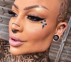 a woman with tattoos and piercings on her face