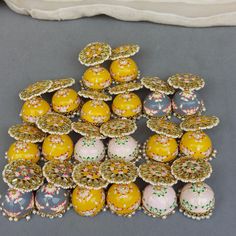 a pile of yellow and pink decorated cookies on a gray tablecloth next to a white pillow