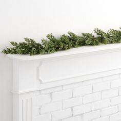 a white brick fireplace with greenery on top