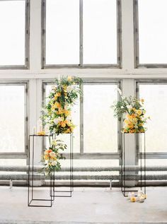 three tall vases with yellow flowers on them