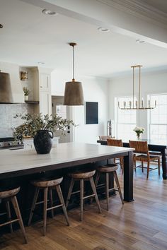 a large kitchen island with stools in front of it and lights hanging from the ceiling