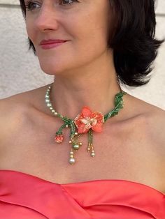 a woman wearing a necklace with flowers and pearls