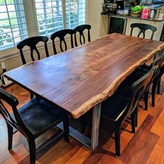 a large wooden table sitting in the middle of a room with black chairs around it