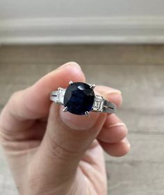 a person holding a ring with a blue stone in it